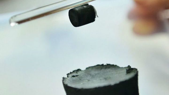 Исследователь демонстрирует, как кусочек нового материала держится на стеклянной палочке за счёт статического электричества 